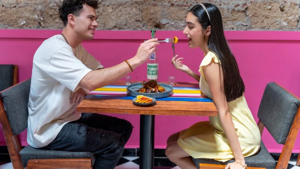 A happy couple sharing food at a vibrant restaurant in Mexico City, enjoying a romantic moment.