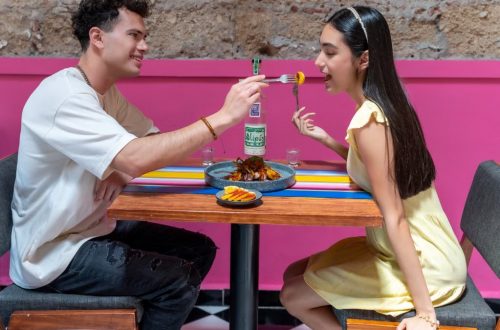 A happy couple sharing food at a vibrant restaurant in Mexico City, enjoying a romantic moment.