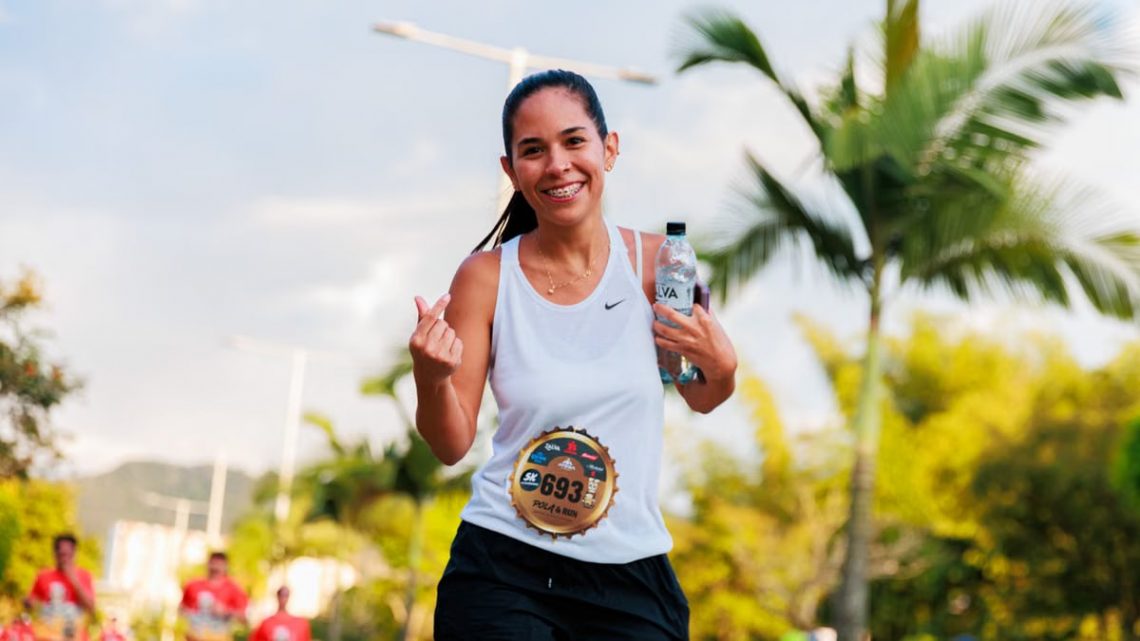 Smiling woman running a marathon outdoors in warm weather.