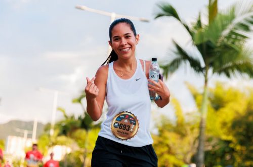 Smiling woman running a marathon outdoors in warm weather.